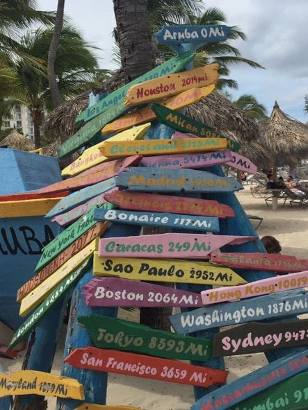 fun sign with city names and distances from Aruba