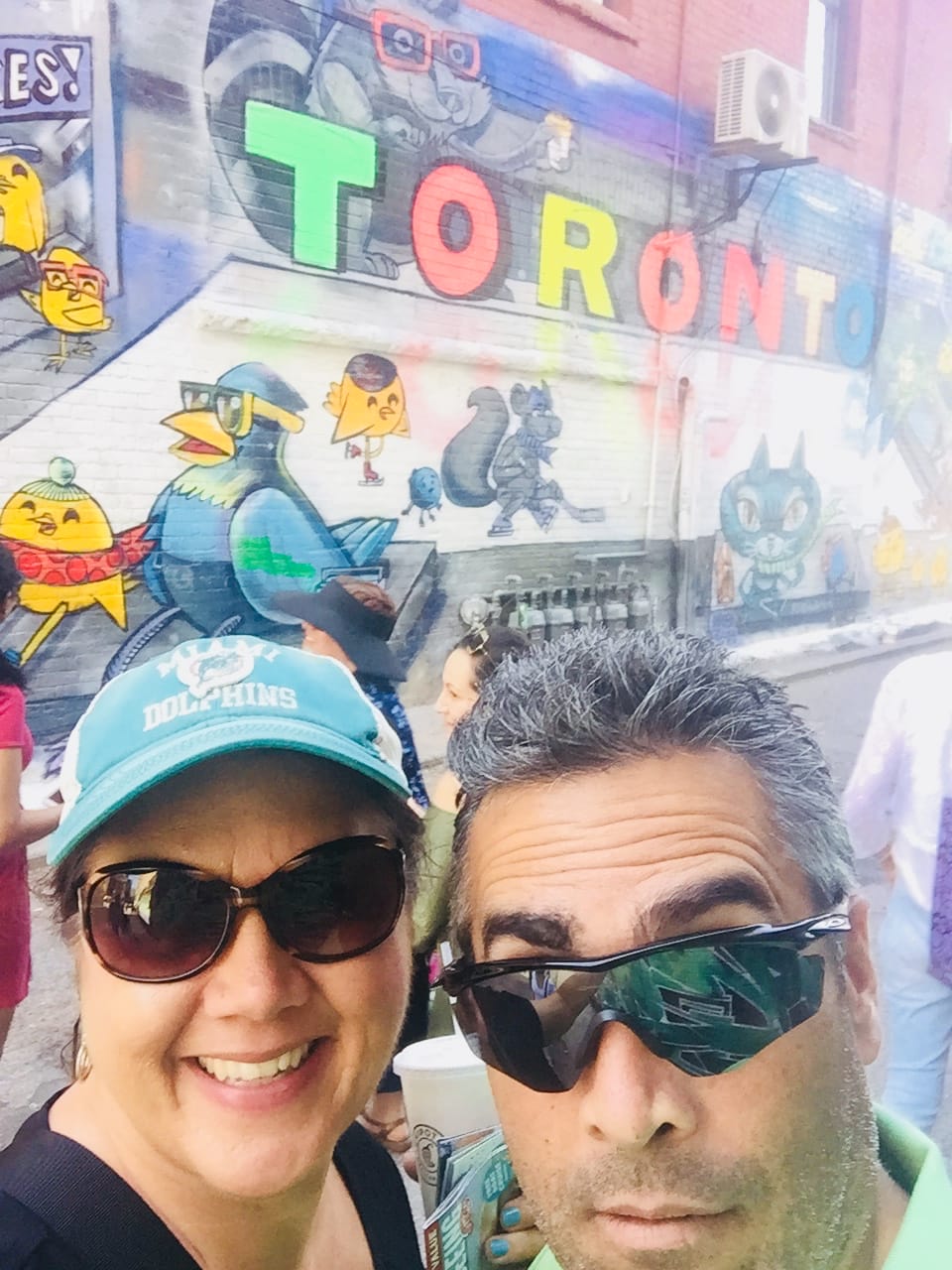 man and woman in front of a Toronto graffiti sign