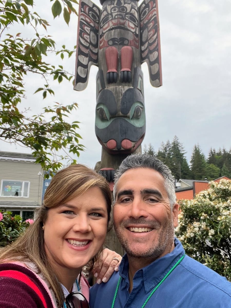 man and woman in front of totem pole