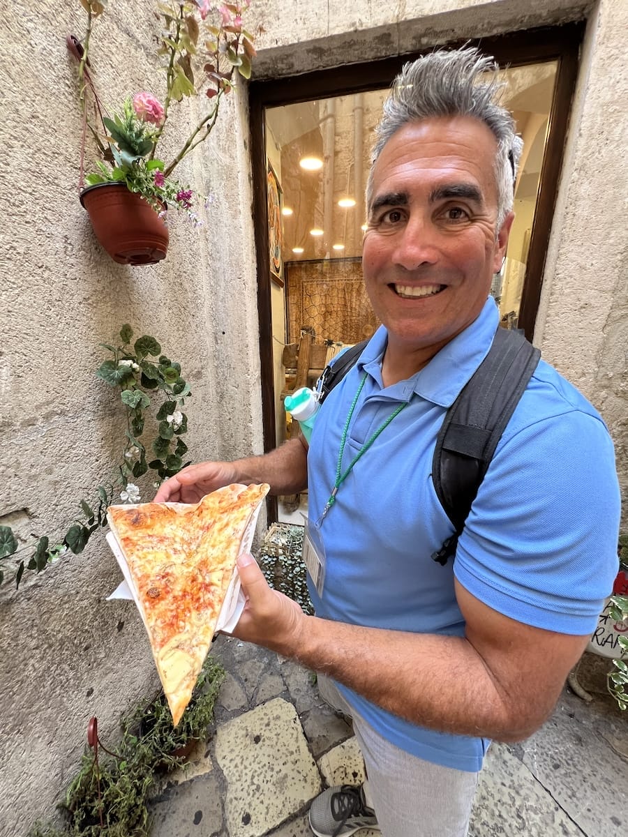 man holding pizza slice in Kotor, Montenegro