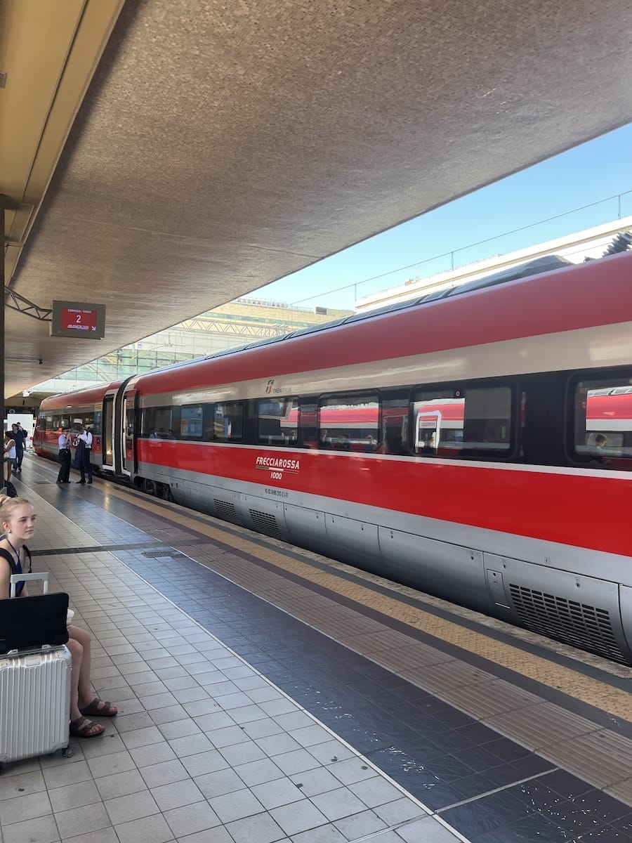 platform sign hanging overhead next to high speed train