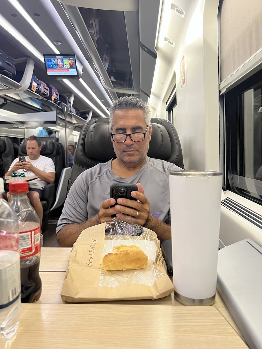 man sitting in train seat on his telephone